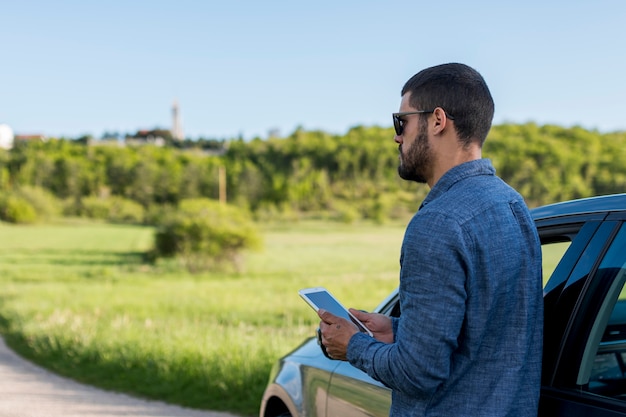 Man next to car using tablet